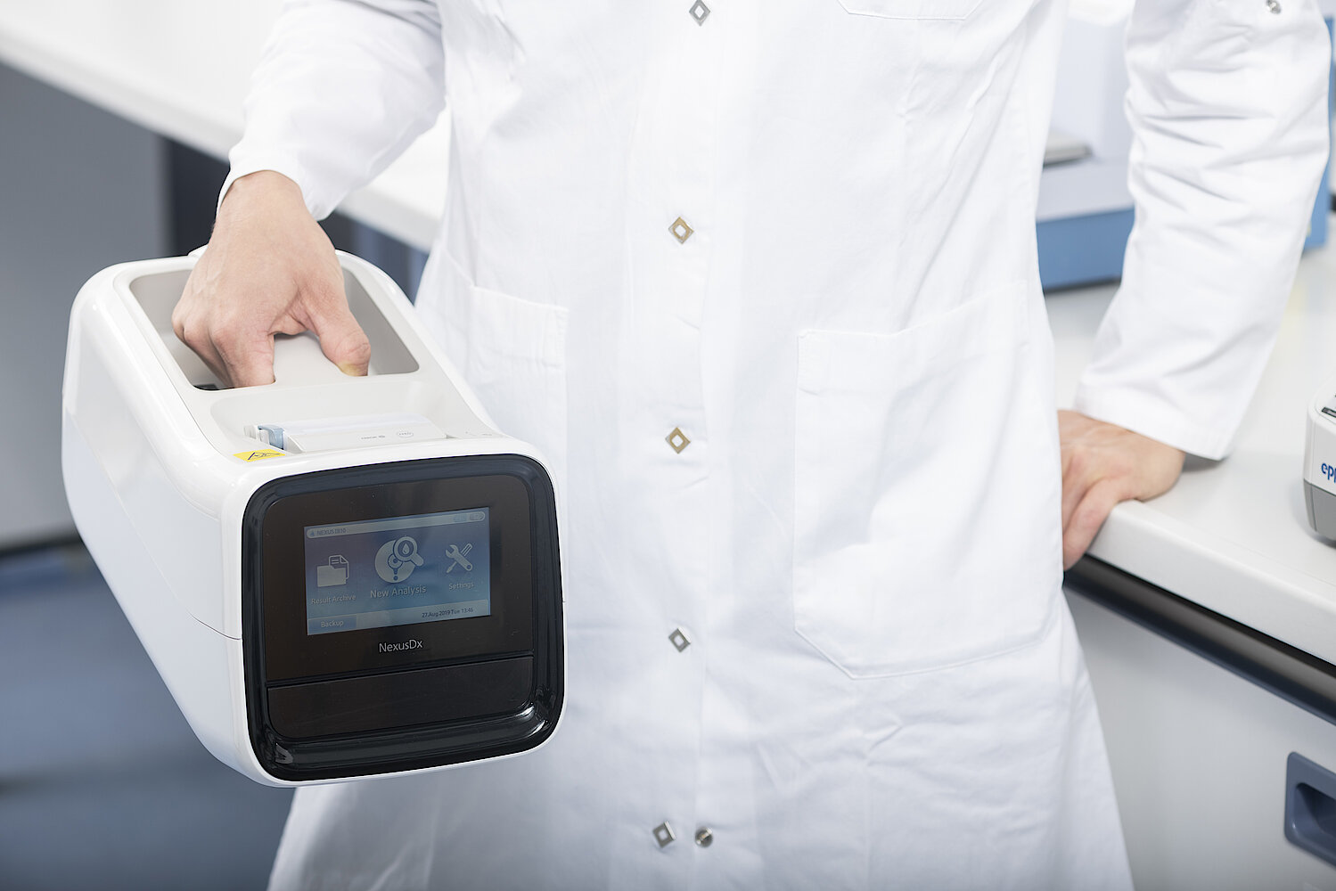 Close up of female research scientist holding the Nexus IB10 analyzer in laboratory setting.