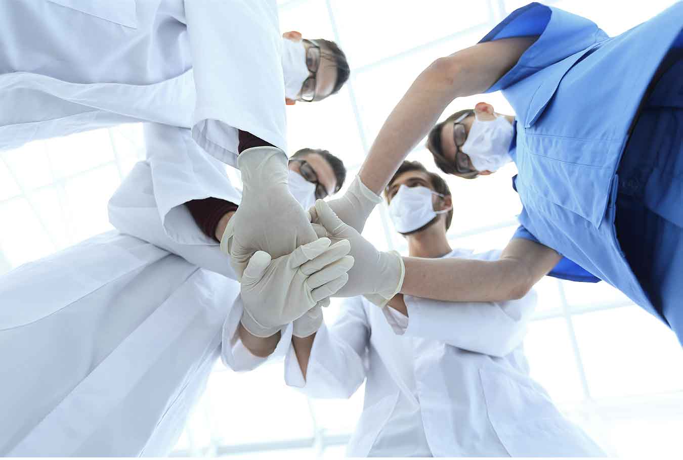 Bottom view of doctors putting hands together showing their unity.